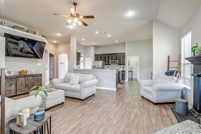 living area with arched walkways, recessed lighting, visible vents, light wood-style floors, and ceiling fan