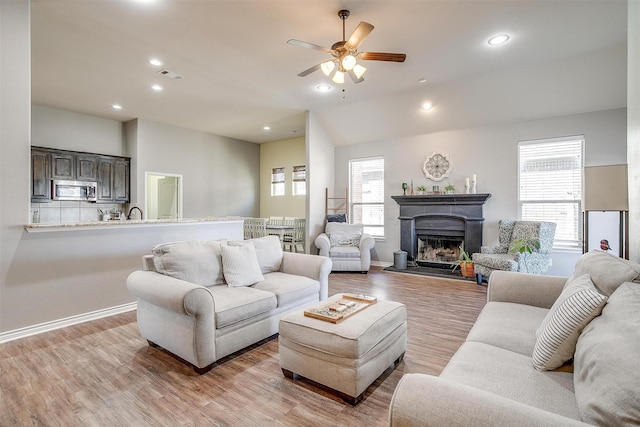 living room with light wood-style floors, recessed lighting, visible vents, and a fireplace with raised hearth