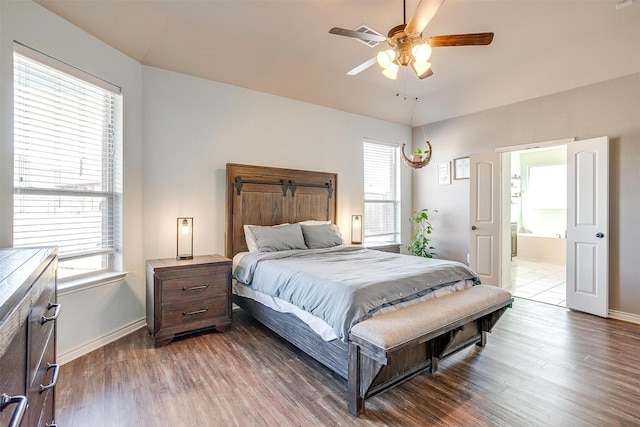 bedroom featuring ceiling fan, ensuite bath, wood finished floors, and baseboards