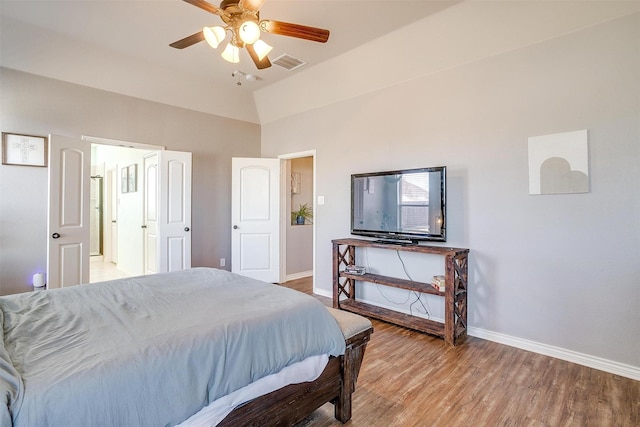 bedroom featuring visible vents, baseboards, ceiling fan, light wood-style flooring, and vaulted ceiling