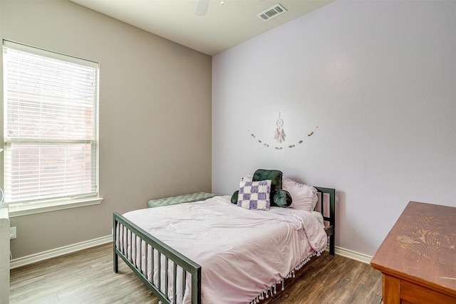 bedroom featuring multiple windows, wood finished floors, visible vents, and baseboards