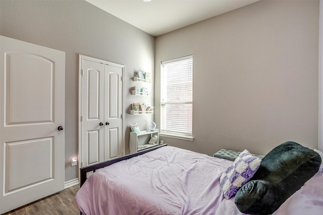 bedroom featuring a closet, wood finished floors, and baseboards