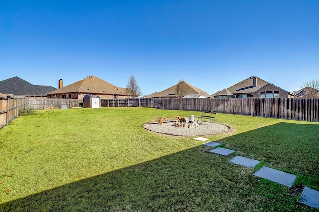 view of yard featuring a fire pit, a shed, an outbuilding, and a fenced backyard