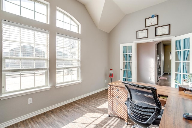 office area featuring arched walkways, vaulted ceiling, baseboards, and wood finished floors