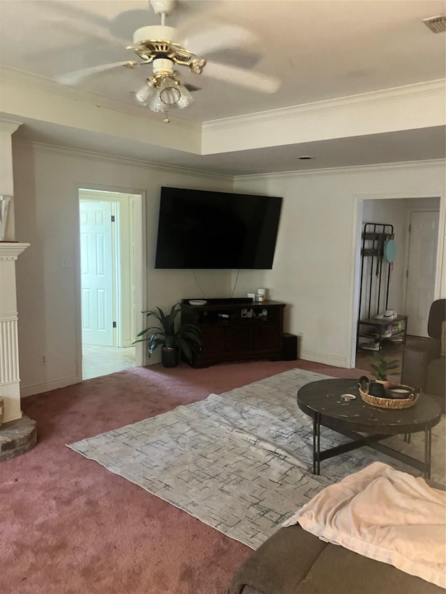 carpeted living area featuring visible vents, a fireplace, a tray ceiling, and ornamental molding