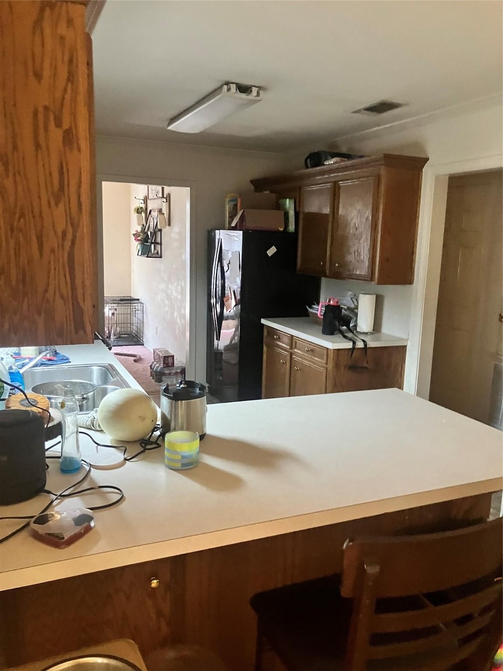 kitchen with a sink, visible vents, a kitchen breakfast bar, light countertops, and freestanding refrigerator