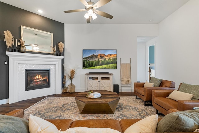 living area featuring ceiling fan, wood finished floors, baseboards, and a tile fireplace