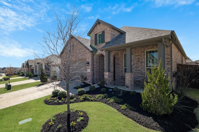 view of front facade featuring brick siding, an attached garage, concrete driveway, and a front yard