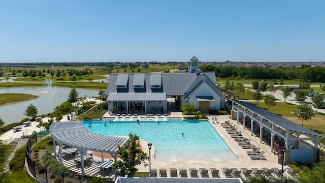 community pool featuring fence, a patio, and a water view