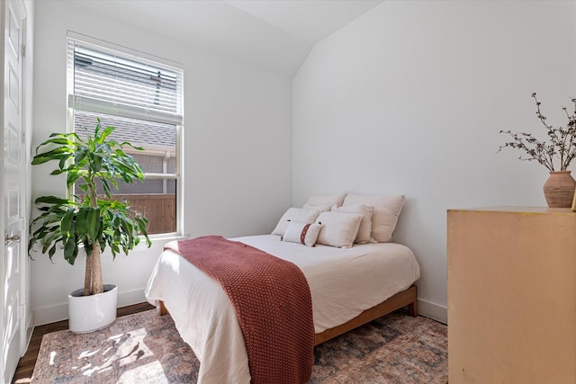 bedroom featuring wood finished floors, baseboards, and vaulted ceiling