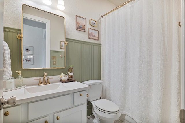 bathroom featuring vanity, toilet, a shower with curtain, and wainscoting