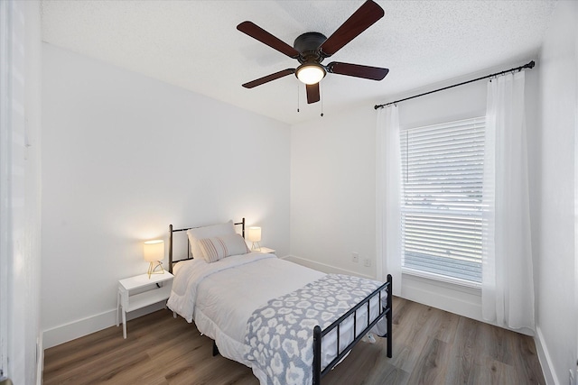 bedroom with a textured ceiling, baseboards, and wood finished floors