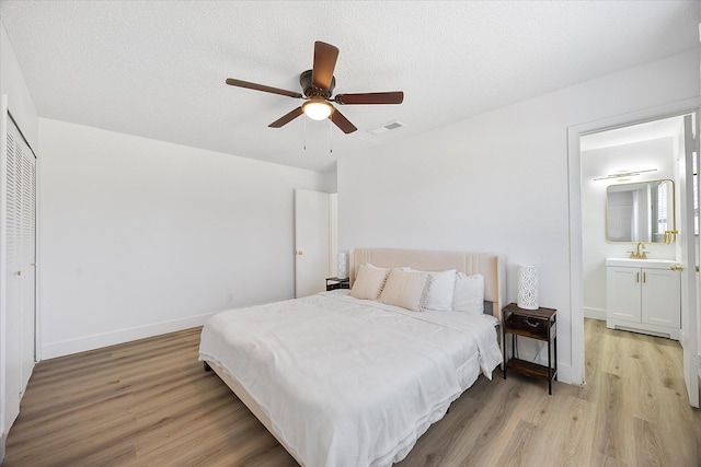 bedroom featuring light wood-type flooring, baseboards, visible vents, and a sink