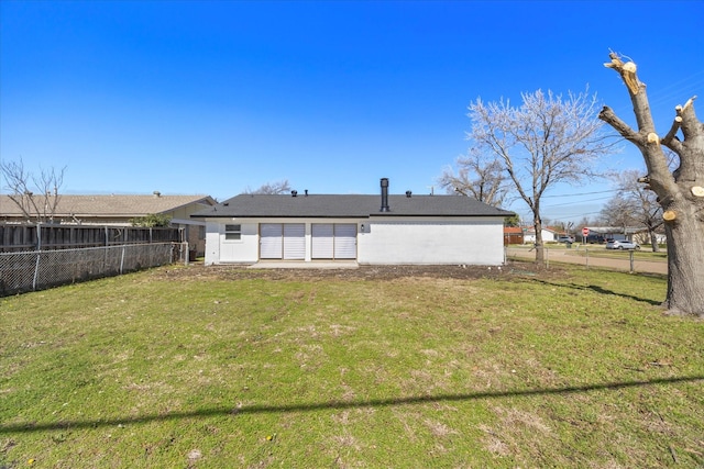 back of property featuring a yard and fence