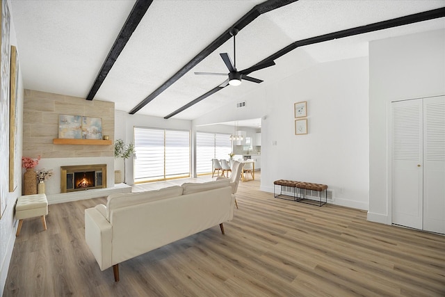 living room with a large fireplace, ceiling fan, a textured ceiling, and wood finished floors