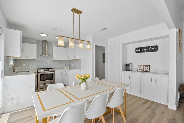 dining area with a textured ceiling, light wood-type flooring, and visible vents