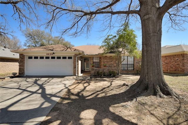 ranch-style home featuring concrete driveway, an attached garage, and brick siding