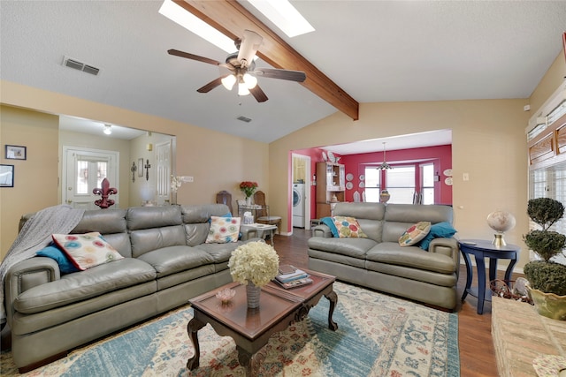 living area with visible vents, lofted ceiling with skylight, washer / clothes dryer, wood finished floors, and ceiling fan