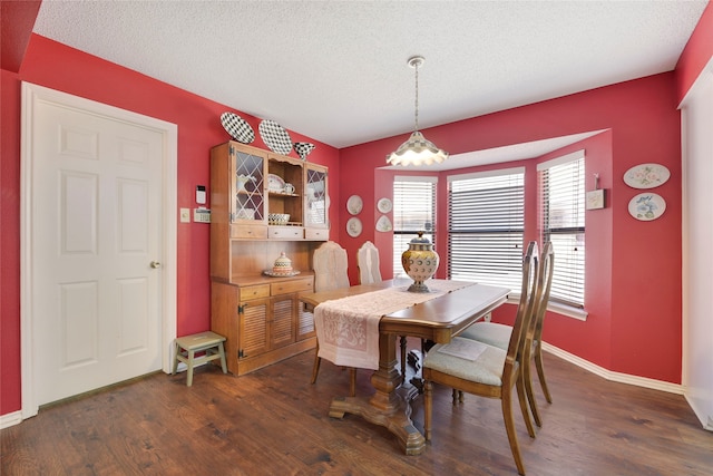 dining room with a textured ceiling, baseboards, and wood finished floors