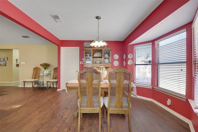 dining room with baseboards, wood finished floors, visible vents, and a textured ceiling