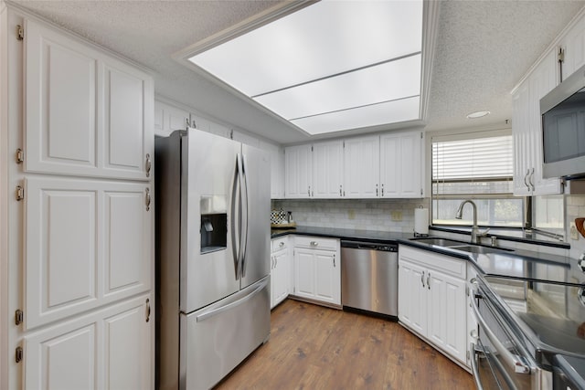 kitchen featuring decorative backsplash, appliances with stainless steel finishes, dark wood-style floors, and white cabinets