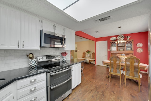 kitchen with dark countertops, visible vents, white cabinets, and stainless steel appliances