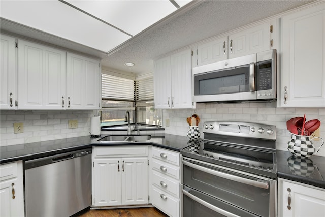 kitchen featuring a sink, dark countertops, white cabinets, and stainless steel appliances