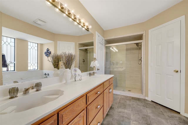 bathroom featuring double vanity, visible vents, a stall shower, and a sink