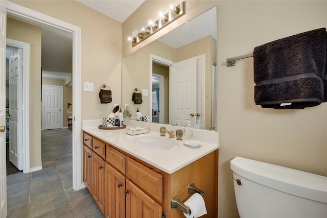 bathroom with toilet, vanity, and baseboards