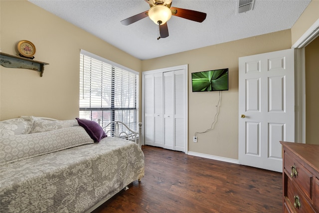 bedroom with baseboards, visible vents, dark wood finished floors, a closet, and a textured ceiling