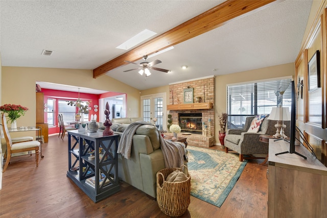 living room featuring visible vents, a brick fireplace, dark wood-type flooring, vaulted ceiling with skylight, and a textured ceiling