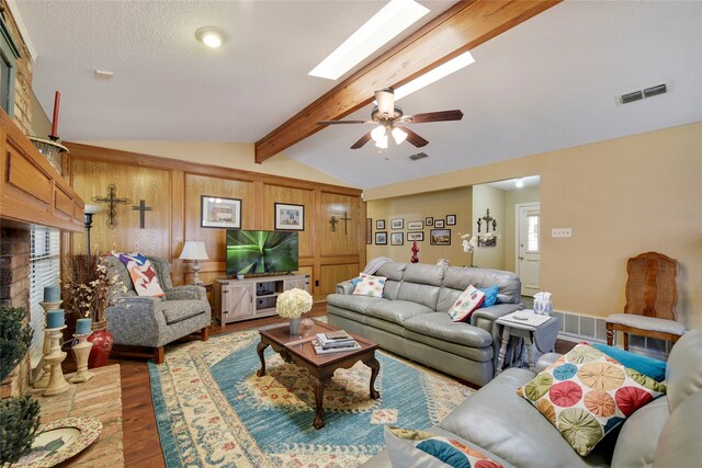 living room featuring lofted ceiling with skylight, visible vents, and wood finished floors