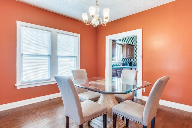 dining area featuring baseboards, a textured ceiling, wood finished floors, and a notable chandelier