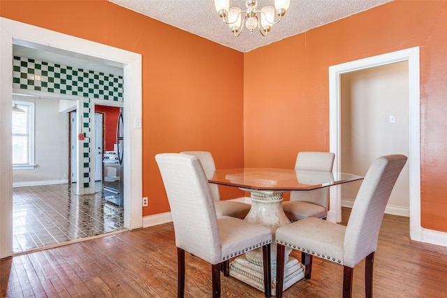 dining space with a chandelier, baseboards, a textured ceiling, and hardwood / wood-style floors