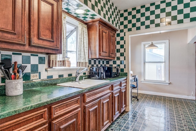 kitchen with plenty of natural light, dark countertops, a sink, and baseboards