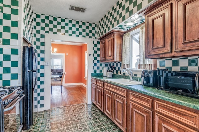 kitchen featuring visible vents, backsplash, a sink, and gas range