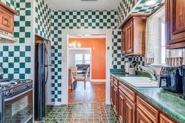 kitchen featuring range with gas stovetop, tasteful backsplash, dark countertops, freestanding refrigerator, and a sink