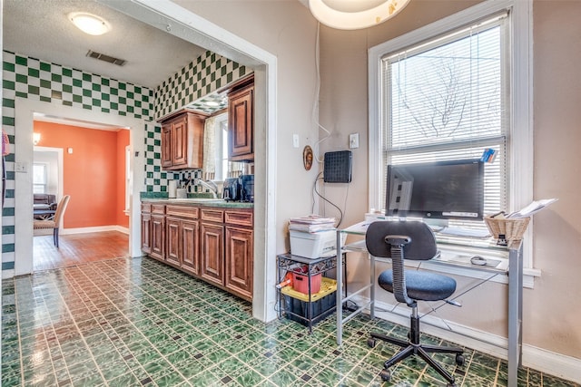 home office with plenty of natural light, visible vents, baseboards, and a textured ceiling