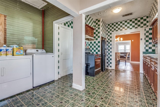 washroom with laundry area, dark floors, visible vents, and washing machine and clothes dryer