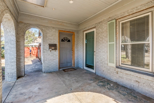 view of exterior entry featuring a patio area and brick siding