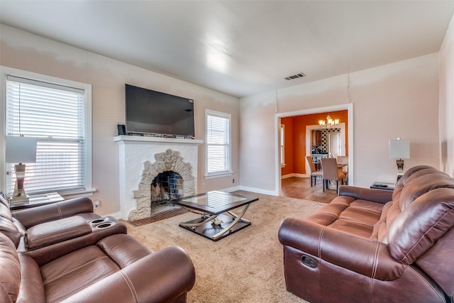 living room with a healthy amount of sunlight, a fireplace, visible vents, and a chandelier