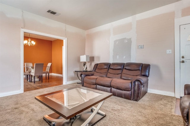 carpeted living room with baseboards, visible vents, and an inviting chandelier