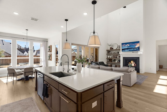 kitchen featuring light wood-style flooring, visible vents, a sink, and a glass covered fireplace