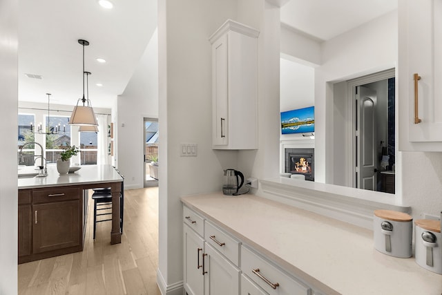 kitchen featuring light countertops, a glass covered fireplace, light wood-type flooring, and a sink