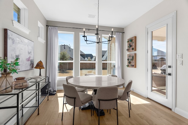 dining room featuring a chandelier, light wood-type flooring, and baseboards