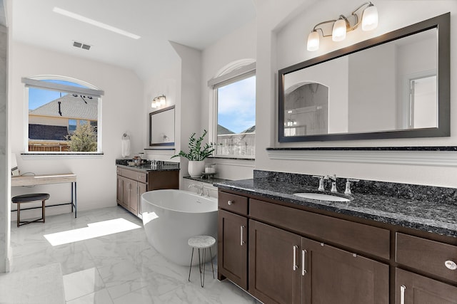 bathroom with visible vents, a sink, marble finish floor, a freestanding bath, and two vanities