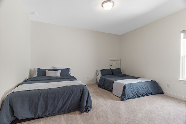 bedroom featuring light carpet and baseboards