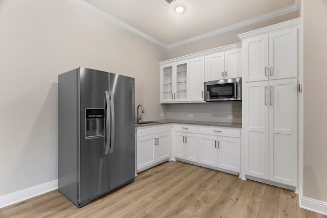 kitchen featuring stainless steel appliances, white cabinets, ornamental molding, and light wood finished floors