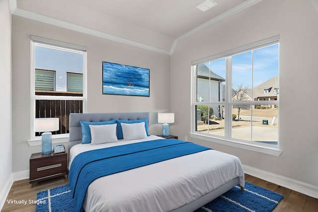 bedroom featuring baseboards, crown molding, visible vents, and wood finished floors