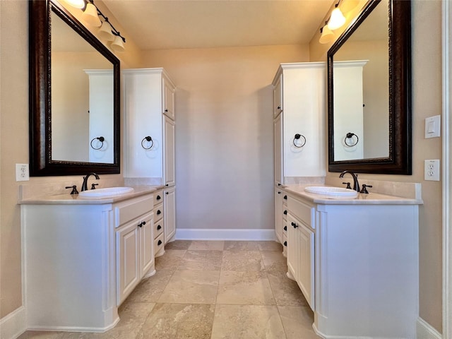 bathroom with baseboards, two vanities, and a sink